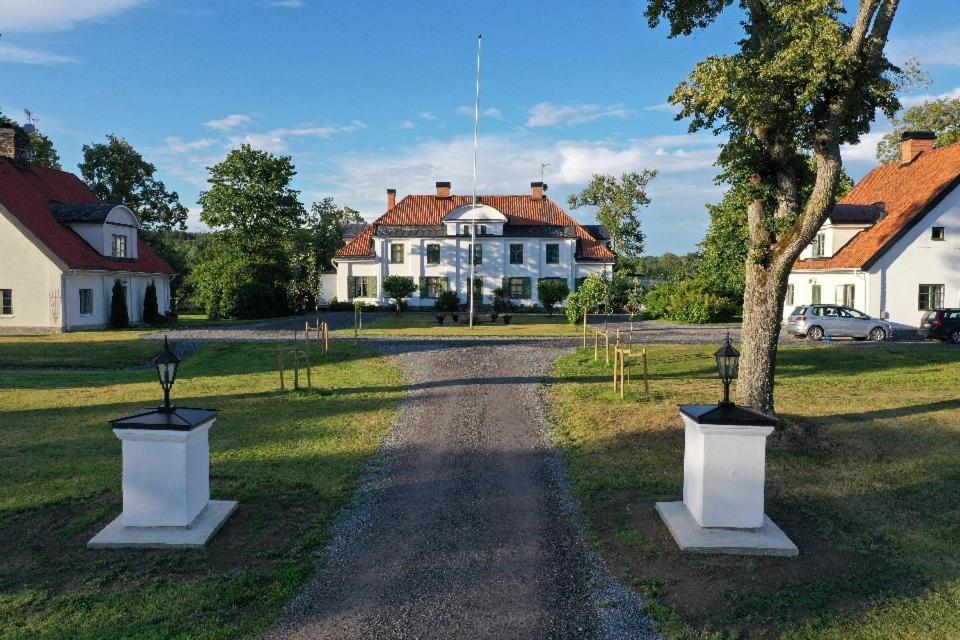 uma estrada de terra com uma árvore e uma casa em Östra Flygeln Grinda Säteri em Malmköping