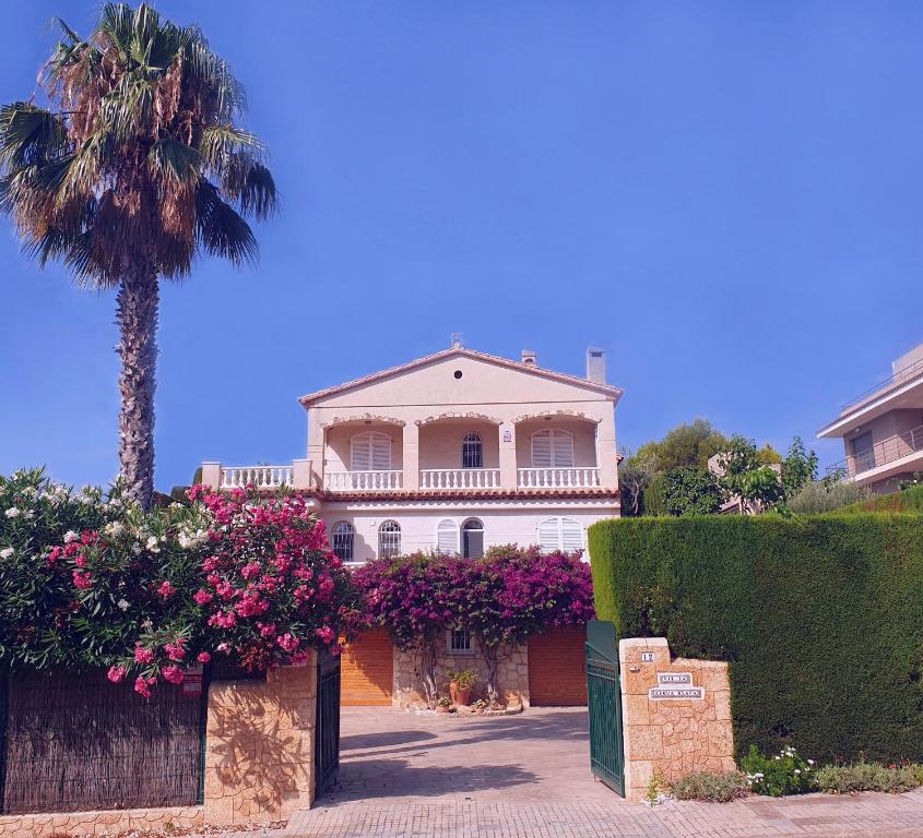 a house with a palm tree and flowers in front of it at Apartamento Aigua Blava in L'Ampolla