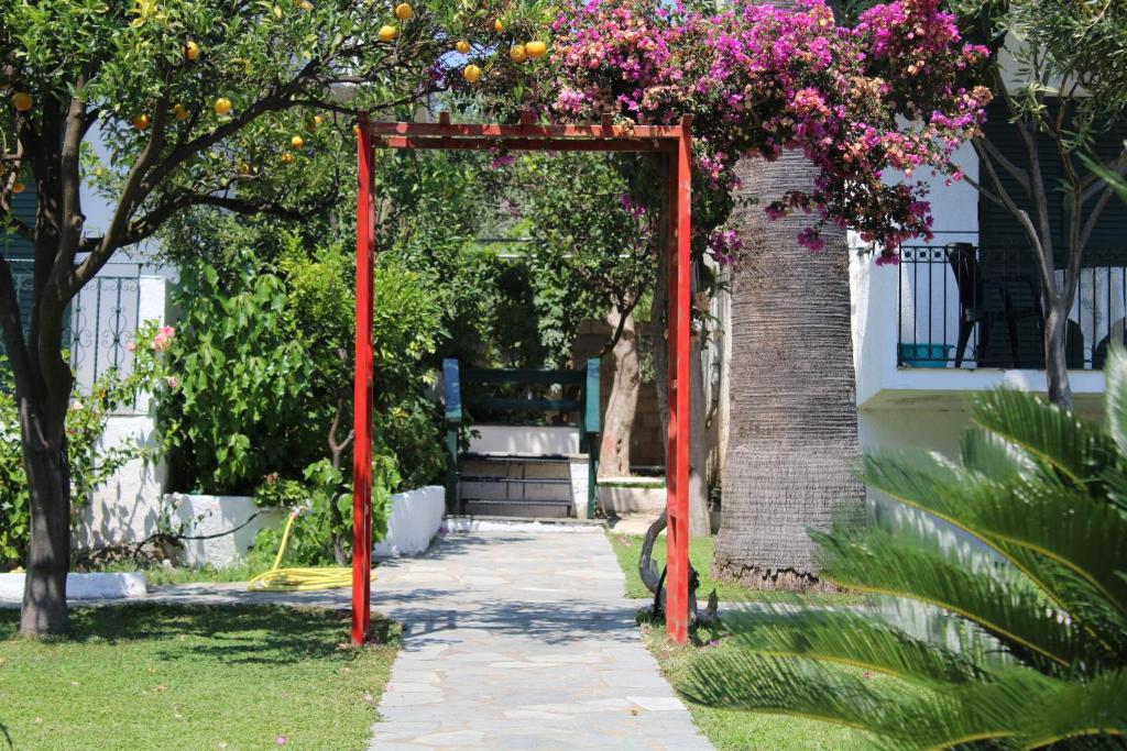 a red archway with flowers on it in a garden at Giovanni Group Apartments in Syvota
