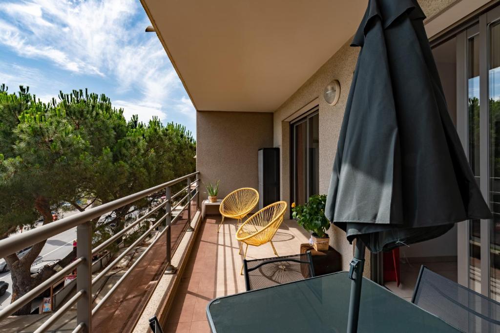 uma varanda com um guarda-sol e 2 cadeiras e mesas em Calvaro - Appartement classé 5 étoiles - vue mer em Calvi