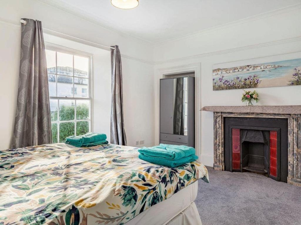 1 dormitorio con 1 cama y chimenea en Lovely Heather House Accommodation 3 kings 1 double sofa en Torquay