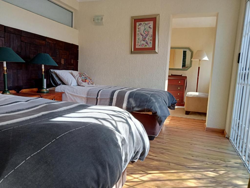 une chambre d'hôtel avec deux lits et un canapé dans l'établissement Duiker's Den at Hulala, à White River