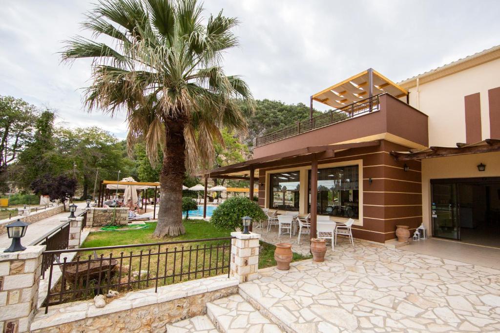 a house with a palm tree in front of it at Riviera Perdika Hotel in Perdika