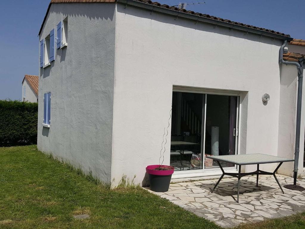- une table de pique-nique à côté d'un bâtiment blanc avec une terrasse dans l'établissement Maison 90m² avec jardin, proche commerces et plages, équipée et idéale famille. - FR-1-494-120, à Vaux-sur-Mer