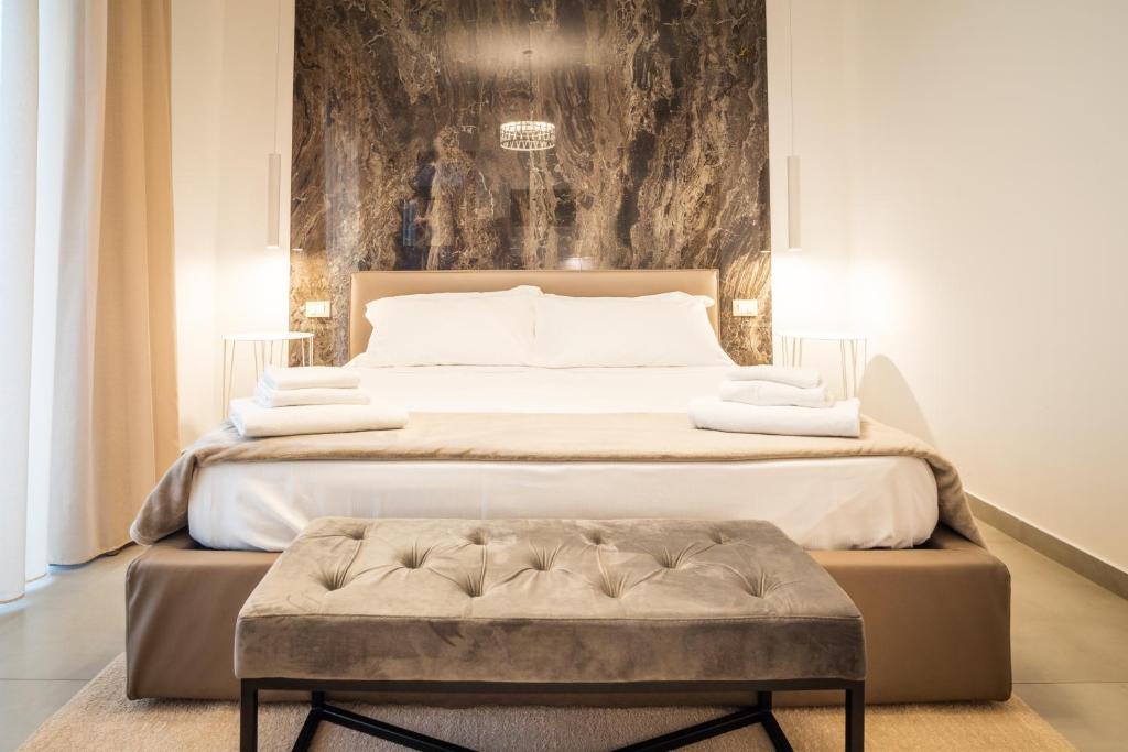 una camera con un grande letto con una panca accanto di Il Crepuscolo Marzamemi a Marzamemi