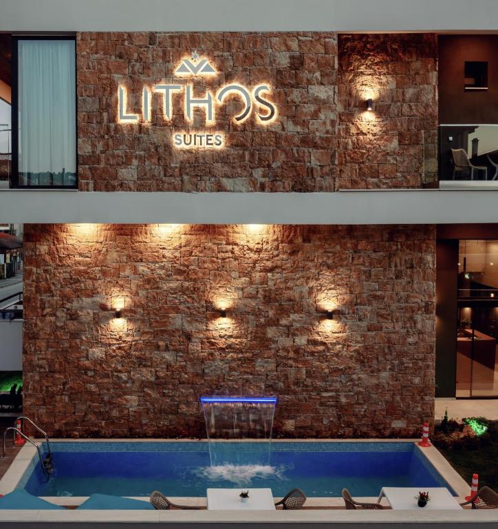 a sign on a brick wall with a swimming pool at Lithos Suites - Nikiti Halkidiki in Nikiti