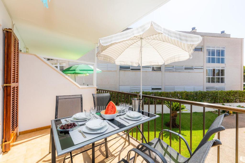 balcón con mesa, sillas y sombrilla en Es Pujol, en Alcudia