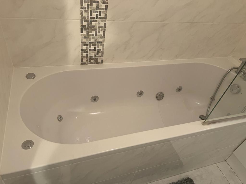 a white bath tub in a bathroom at Lovely 2 bedroom flat in the heart of water Wimbledon in London