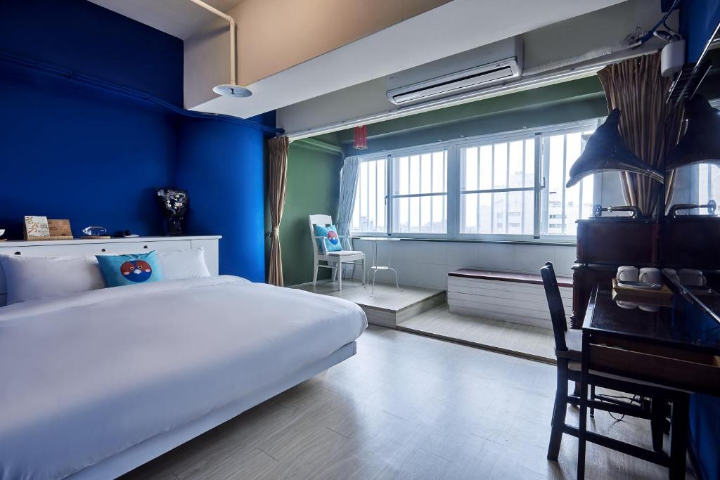 a bedroom with a white bed and a blue wall at 安蘭居旅店 An Lan Jie Hotel in Chiayi City
