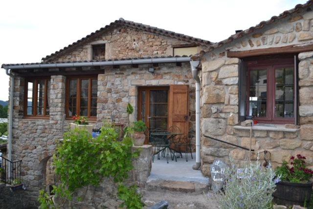 ein Steinhaus mit einer Terrasse davor in der Unterkunft Deux chambres d hôtes attenantes avec salon salle à manger privatif en Cévennes Gardoises in Saint-Jean-du-Gard