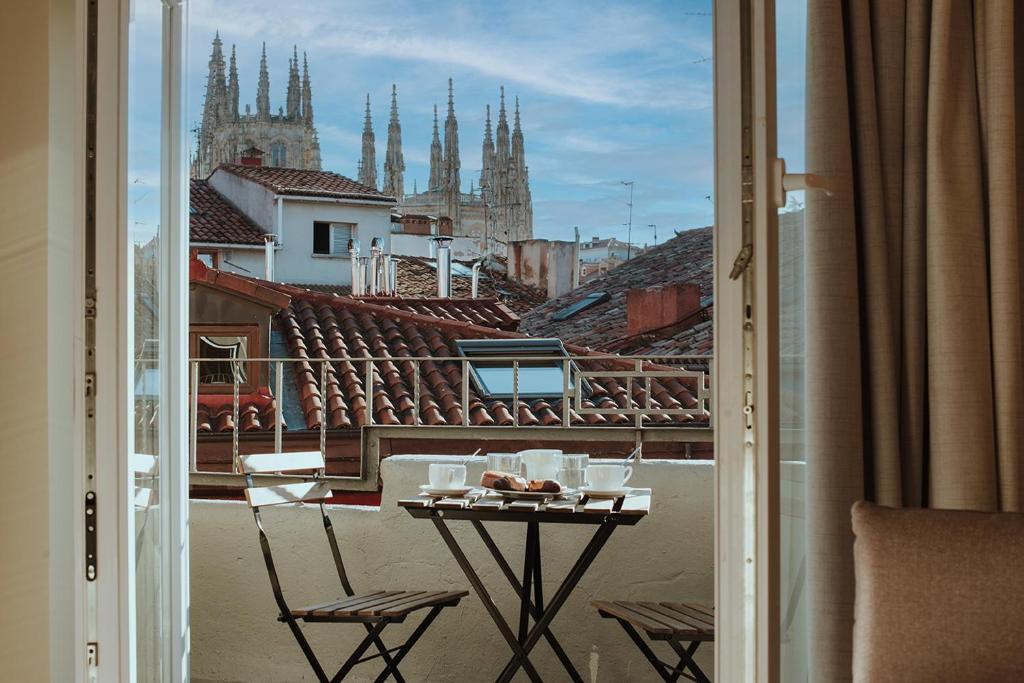 a table and chairs on a balcony with a view of a city at Apartamentos BURGOSUITES in Burgos