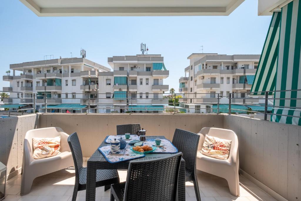 een tafel en stoelen op een balkon met gebouwen bij Pineta Mare Flat in Gallipoli