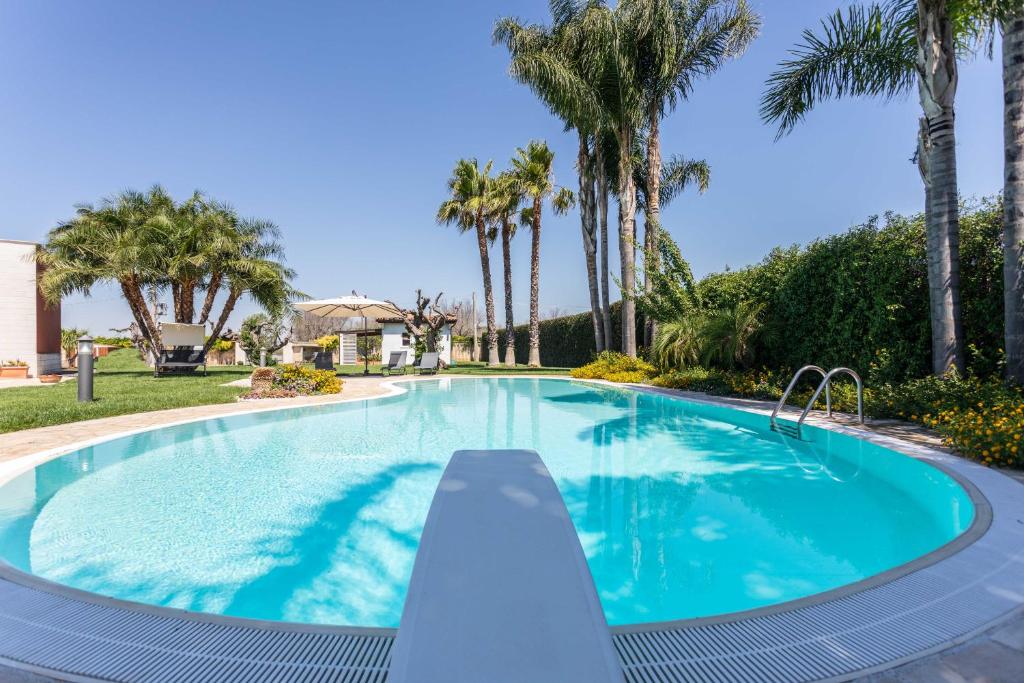 una piscina con palmeras en el fondo en Green House in Villa con Piscina en San Donato di Lecce
