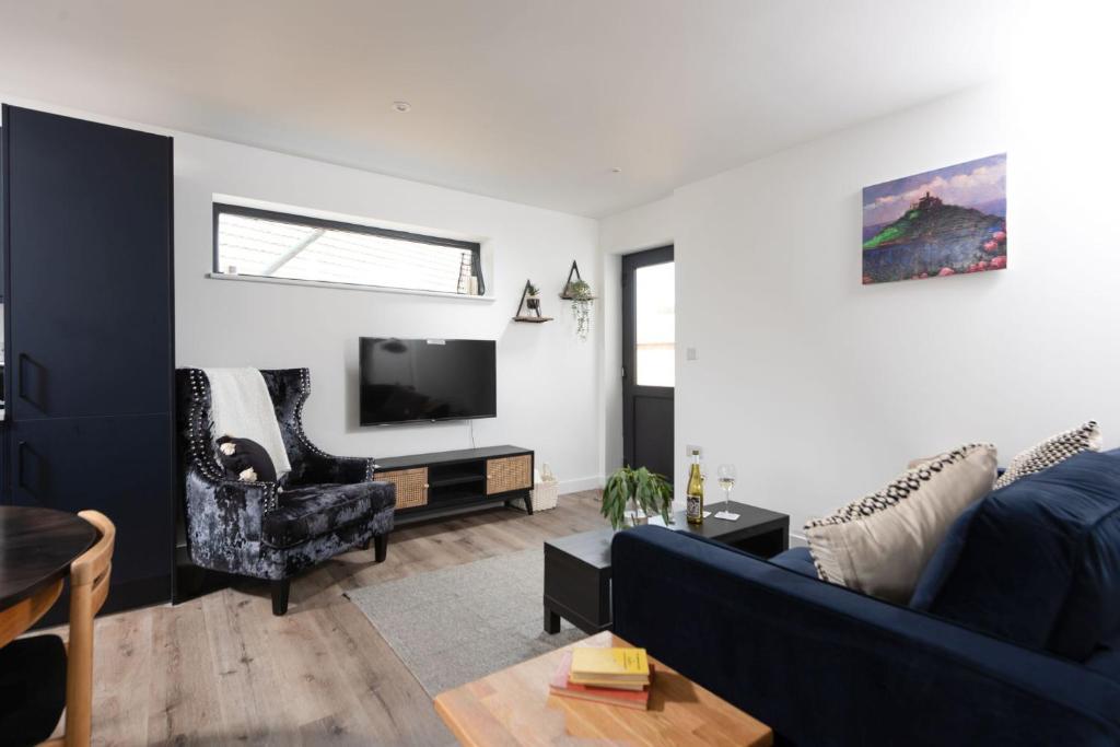 a living room with a blue couch and a tv at Bay Dream, St Ives in Carbis Bay