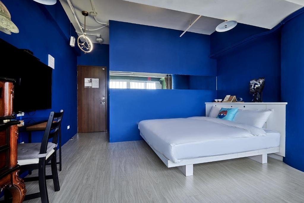 a blue bedroom with a white bed and a chair at 安蘭居旅店 An Lan Jie Hotel in Chiayi City