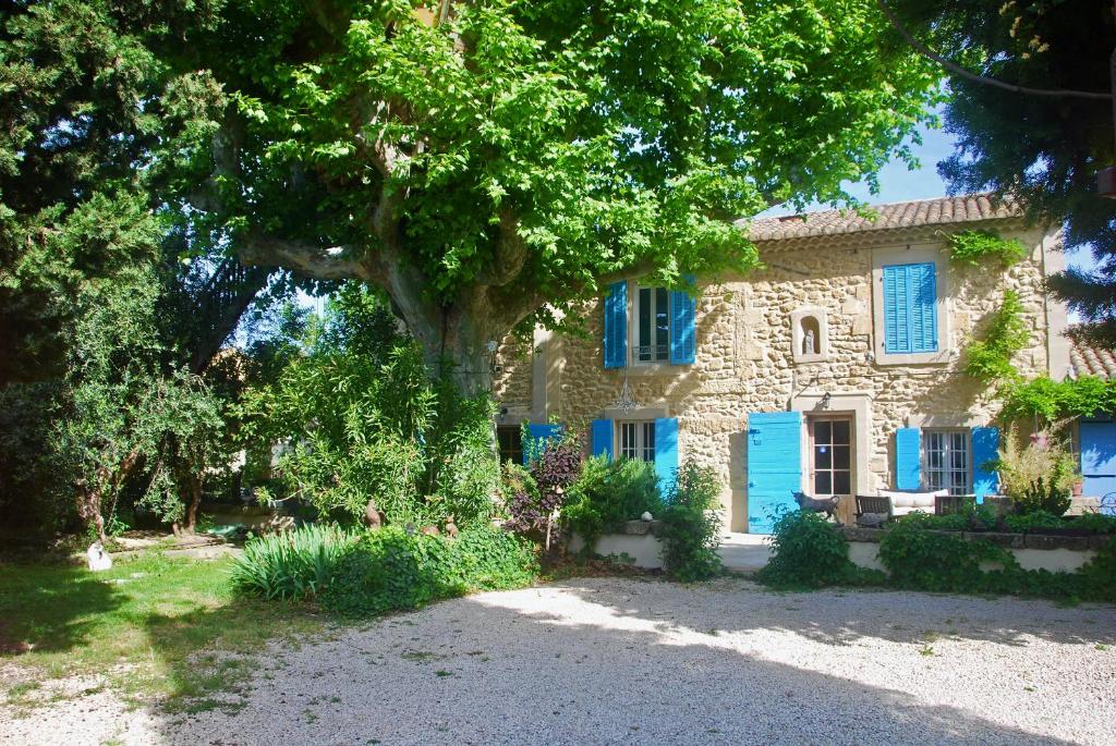 une maison en pierre avec des fenêtres bleues et un arbre dans l'établissement Les Volets Bleus Provence, à Salon-de-Provence
