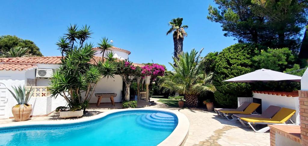 a swimming pool in front of a house with palm trees at Casa Del Sol in L'Ametlla de Mar