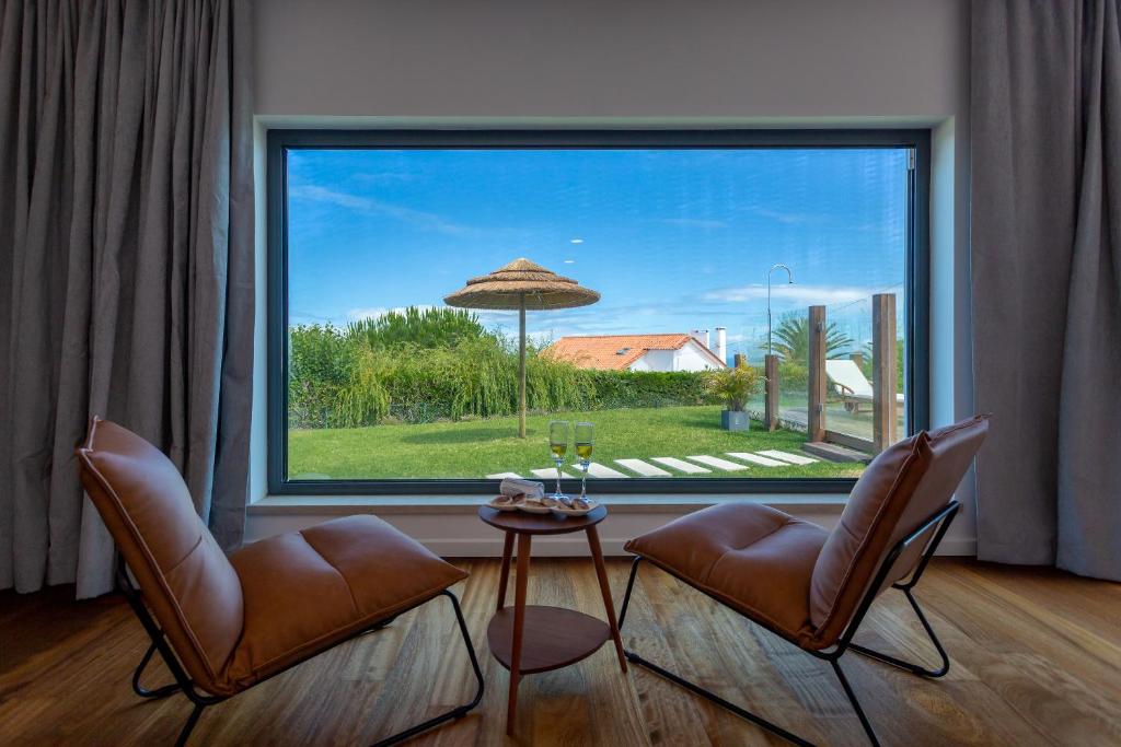 a living room with two chairs and a large window at BeGuest SunRoca Suites in Colares