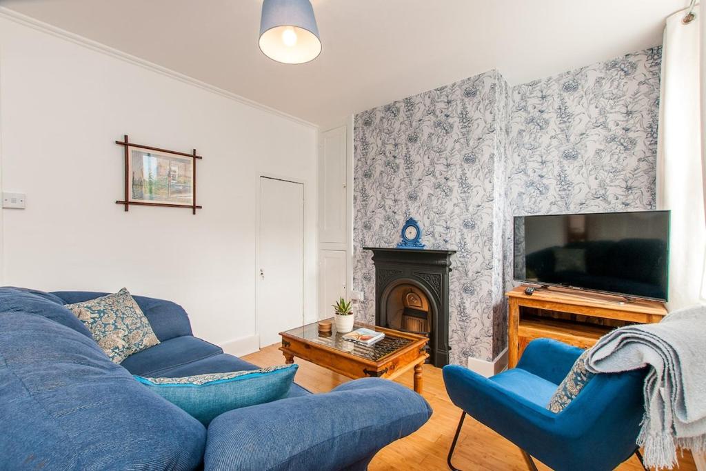 a living room with a blue couch and a tv at Magdala Cottage -village Location- Dog Friendly in Kent