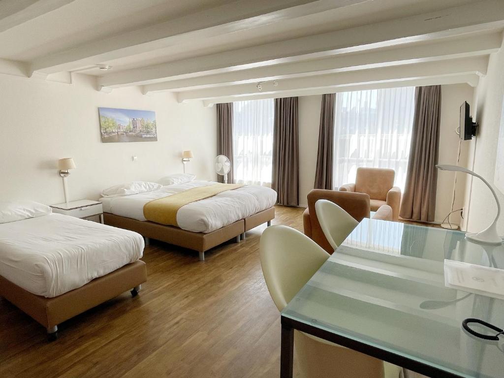 ein Hotelzimmer mit 2 Betten und einem Tisch in der Unterkunft Hotel Residence Le Coin in Amsterdam