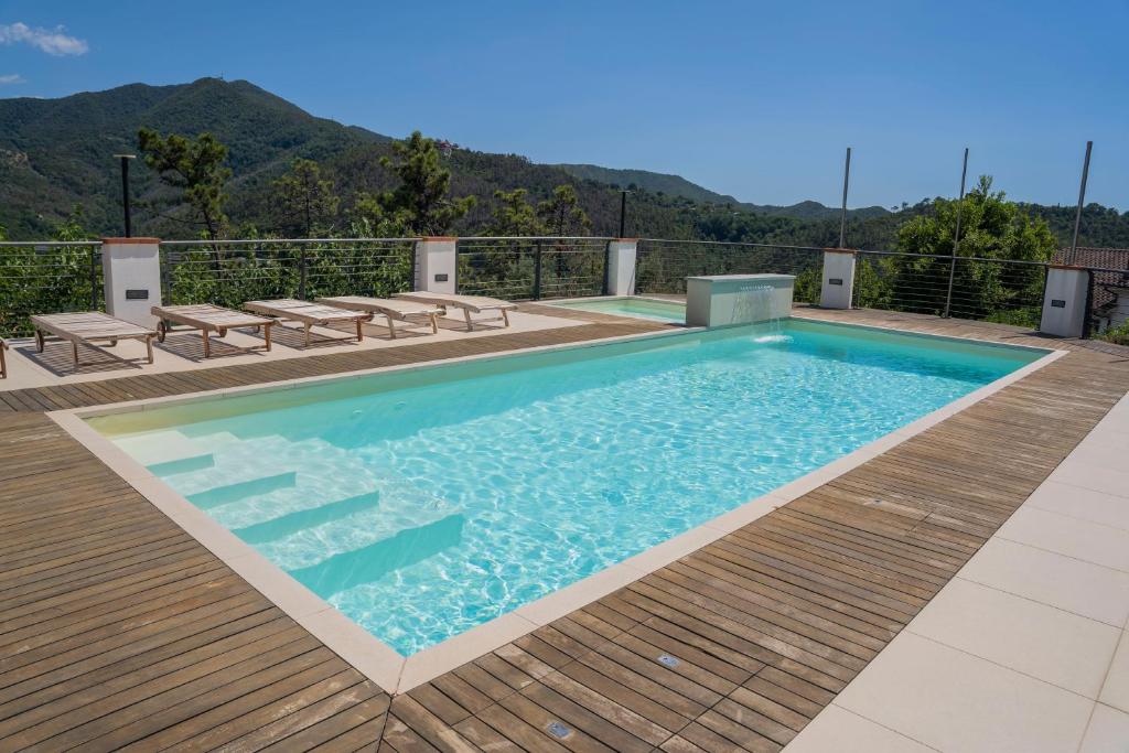 una piscina con terraza de madera y montañas de fondo en 066 - VILLA LETIZIA, Elegante 3 PISCINA e Natura, 10 minuti da MARE e SPIAGGIE, en Casarza Ligure