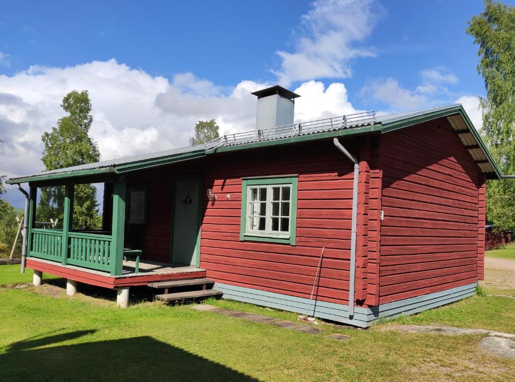 eine rote Hütte mit einer Veranda und einem Fenster in der Unterkunft Ekesberget Stugby Pippi Stuga in Ekshärad