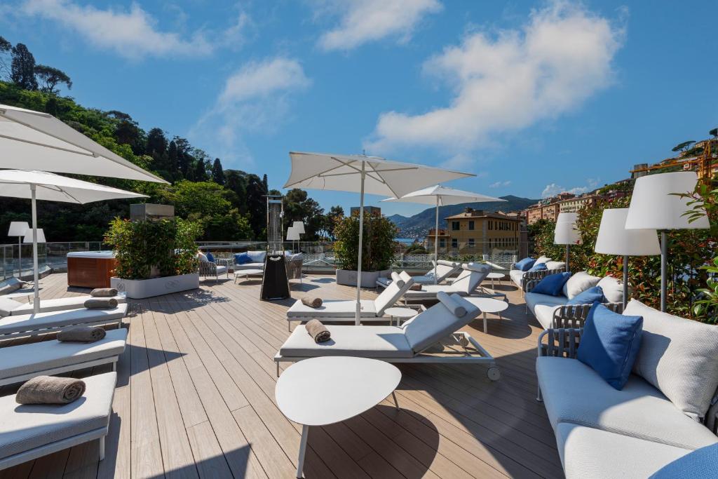a patio with lounge chairs and tables and umbrellas at Carrick Hotel Camogli Portofino Coast in Camogli