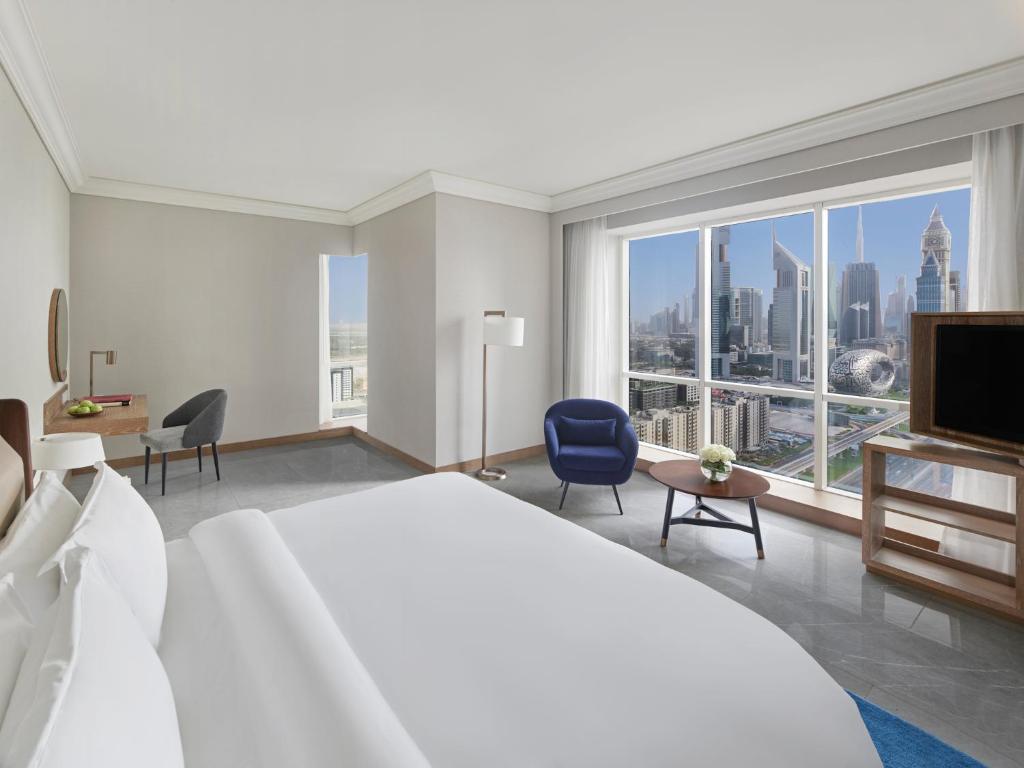 a bedroom with a large bed and a large window at Fairmont Dubai in Dubai