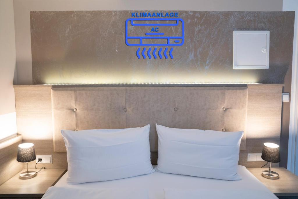 Alpha & Omega Hotel في شتوتغارت: غرفة نوم مع سرير مع وسادتين بيضاء