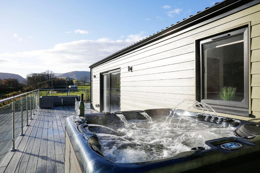 a bath tub with water in it on a deck at Castlehill cabin with a hot tub in Peebles