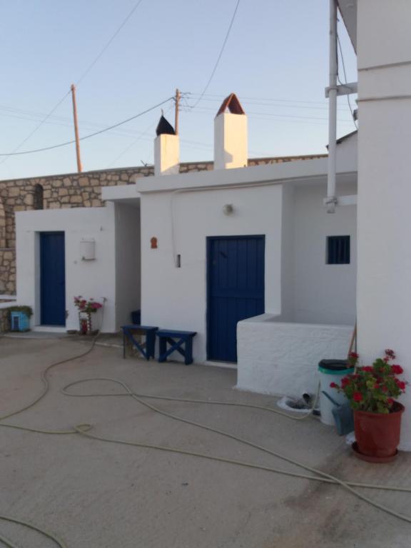 - un bâtiment blanc avec des portes bleues et une terrasse dans l'établissement EVELYN'S COUNTRY HOUSE, à Afiartis