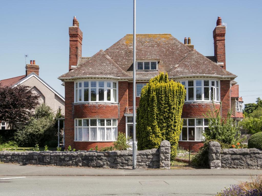 a red brick house with a tree in front of it at Seawinds 2a in Colwyn Bay