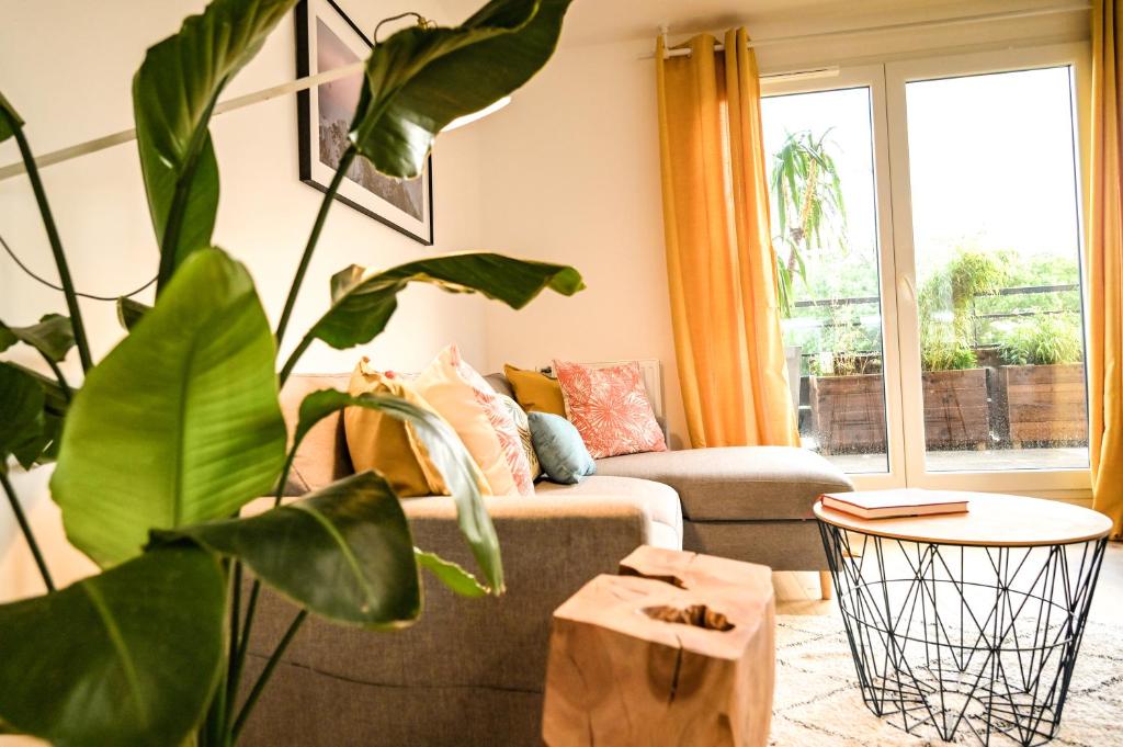 a living room with a couch and a plant at L'Olympique: appartement cosy, vue canal grande terrasse et parking in Vaires-sur-Marne