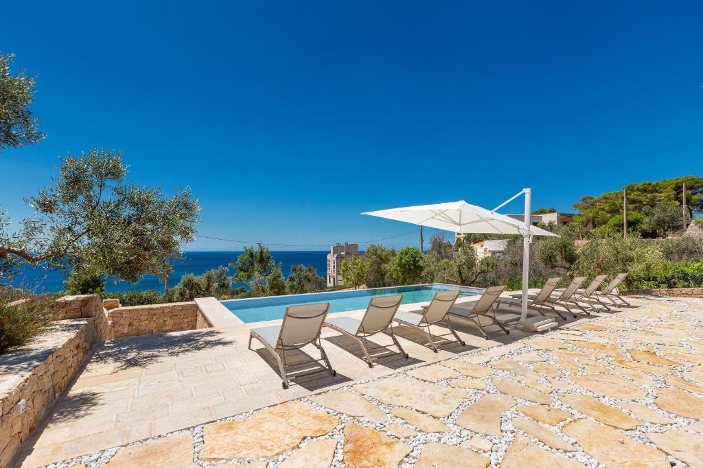 a group of chairs and an umbrella next to a swimming pool at Villa Lodrea by Perle di Puglia in Morciano di Leuca