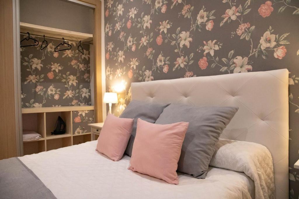 1 dormitorio con 1 cama con almohadas rosas y grises en El Hidalgo, en Almagro