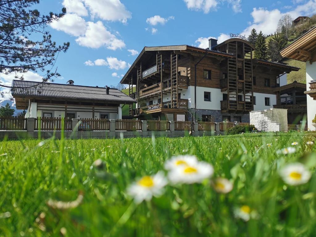 uma casa no fundo com flores no primeiro plano em Der Zirmhof in Saalbach em Saalbach Hinterglemm