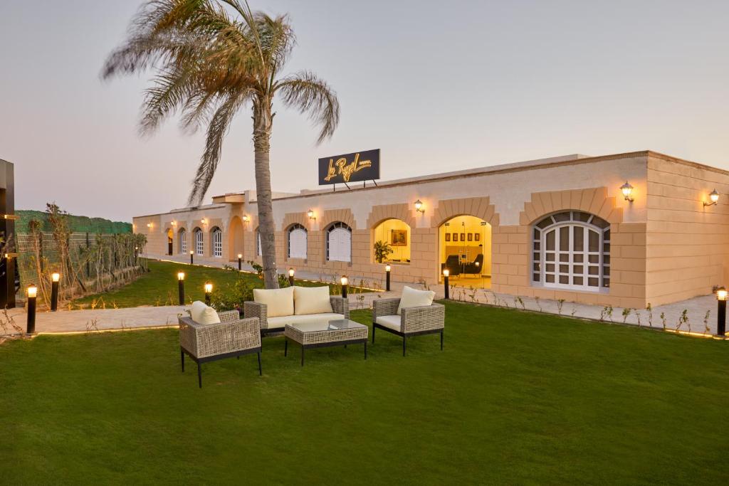 a building with chairs and a palm tree in front of it at Le Royal Marina Hotel in El Alamein