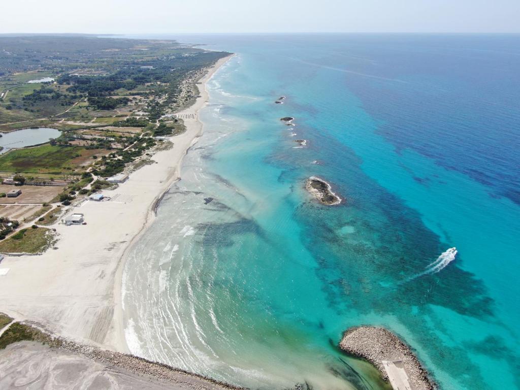 una vista aerea di una spiaggia con barche in acqua di House Salento Central Rooms a Torre San Giovanni Ugento