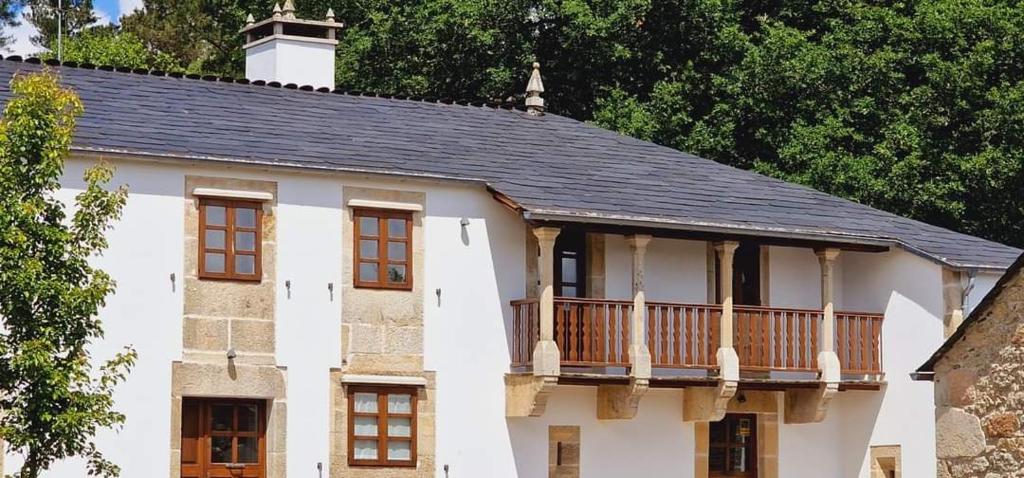 Una gran casa blanca con balcón. en Habitaciones La Cuevona de Guitiriz Lugo en Guitiriz