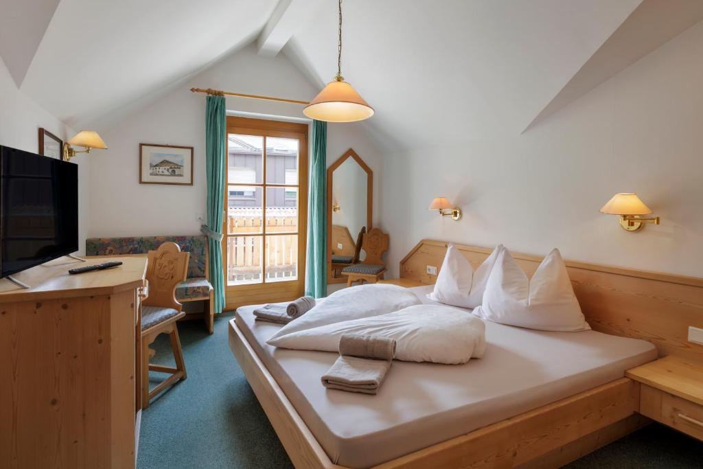a bedroom with a bed with white pillows and a television at Garni Ziernheld in Malles Venosta