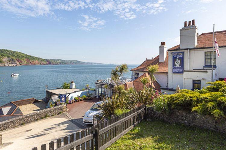 a house with a car parked next to a body of water at 3 Bed - Smugglers Cottage in Torquay