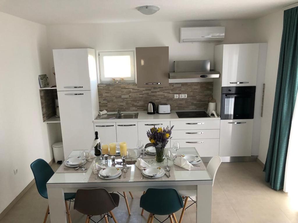 a kitchen with a white table and chairs and a table at Apartman MIR in Makarska