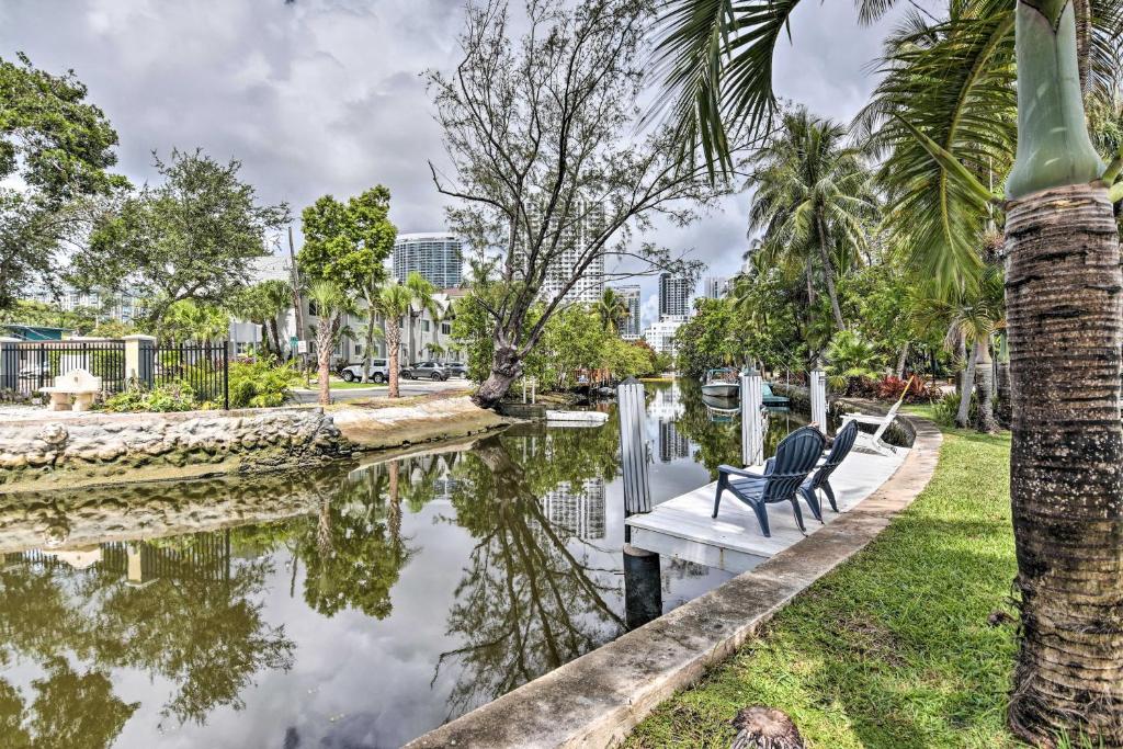 a bench next to a canal with palm trees at Canal-Front Condo Walk to Downtown Ft Lauderdale! in Fort Lauderdale