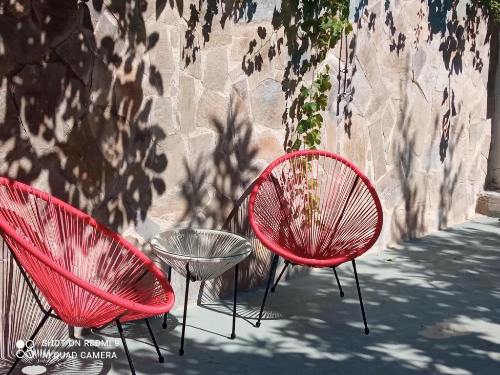two red chairs and a table in front of a wall at Xaido's House near airport port sea in Artemida