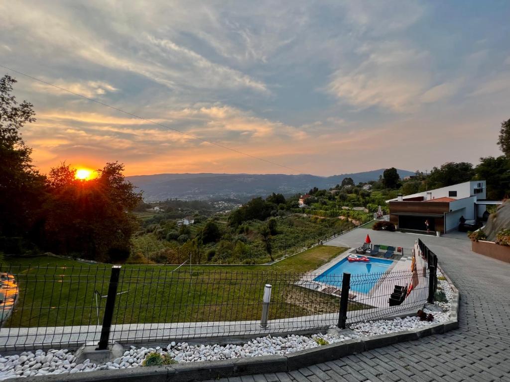 - une vue sur la piscine et le coucher de soleil en arrière-plan dans l'établissement Land'Him House, à Ponte da Barca