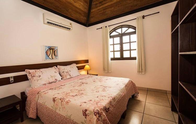 a bedroom with a large bed and a window at Pousada Caminho do Mar in Imbassai