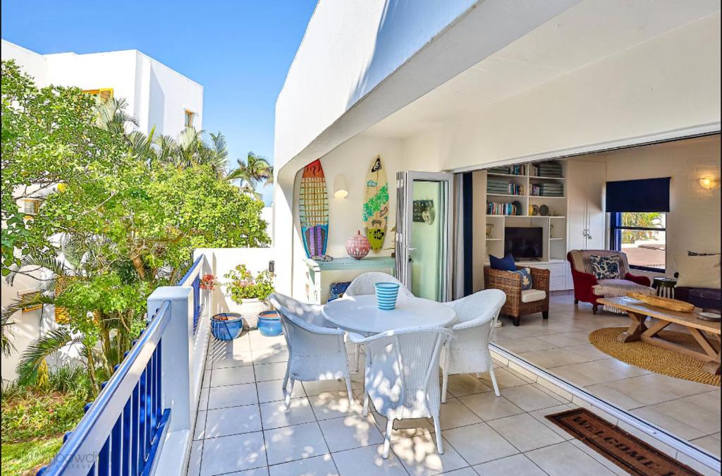 een terras met een tafel en stoelen op een balkon bij Mediterranean beach villa - FAMILIES ONLY in Ballito