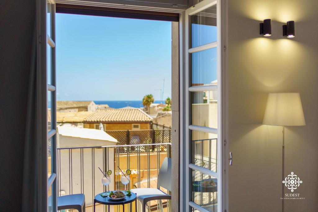 a room with a balcony with a view of the ocean at Matteotti Luxury Residence in Siracusa