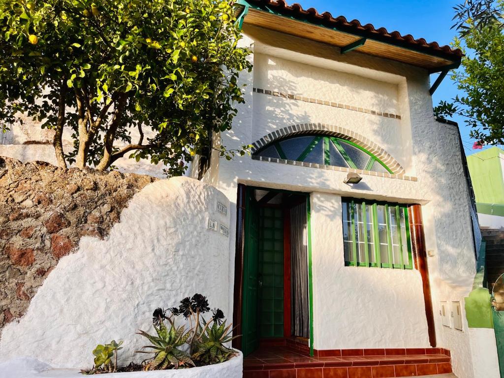 una pequeña casa blanca con una puerta verde en Cueva El Retamal en Juncalillo