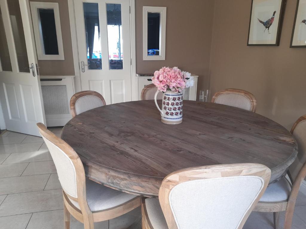 uma mesa de madeira com cadeiras e um vaso de flores em 112 Roseberry Hill em Newbridge